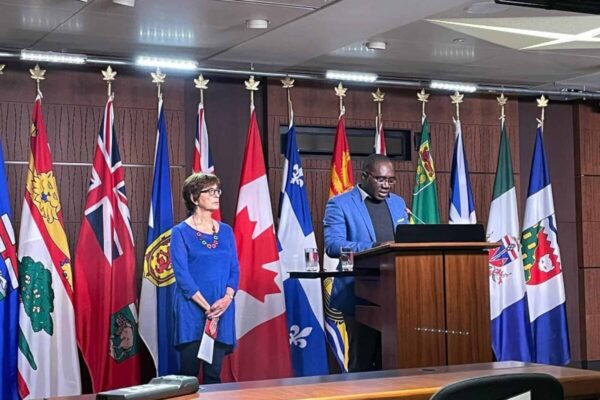 Fr Jacques Nzumbu addresses the parliamentary press conference in Ottawa October 31, 2022, as CJI Executive Director Jenny Cafiso waits for her turn to speak.